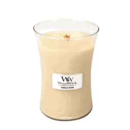 Una grande candela a forma di clessidra in un barattolo di vetro con uno stoppino di legno è etichettata "Vanilla Bean Woodwick - Candela Grande", che si muove delicatamente da un lato all'altro. La cera è color crema.