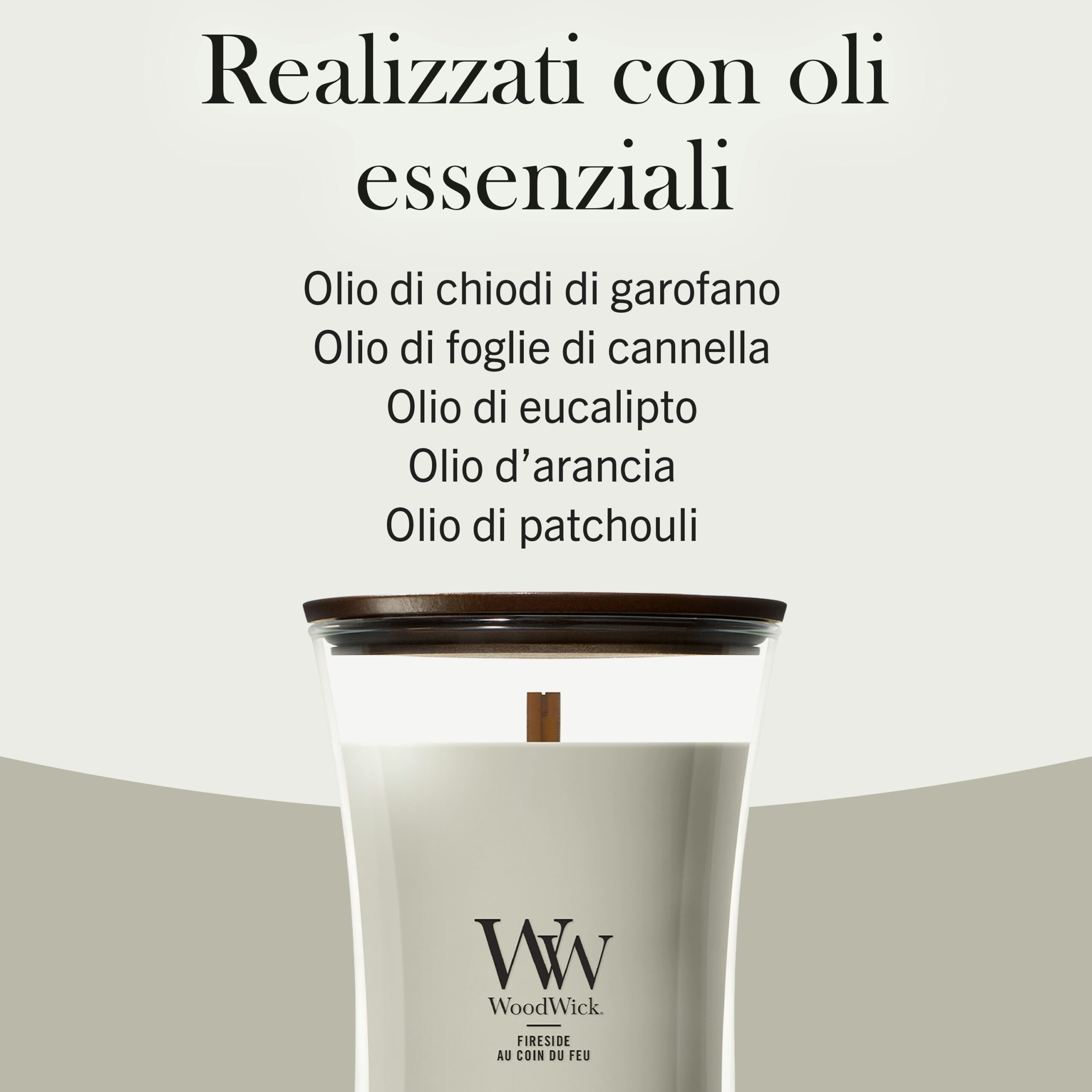 Fireside – Candela Media Woodwick Giara media 4 Una candela Fireside - Candela Grande Woodwick con un'etichetta in italiano che elenca i suoi oli essenziali: chiodi di garofano, foglia di cannella, eucalipto, arancia e patchouli. La candela bianca richiama la classica collezione Fireside ed è dotata di coperchio e stoppino in legno, presentata su uno sfondo neutro.