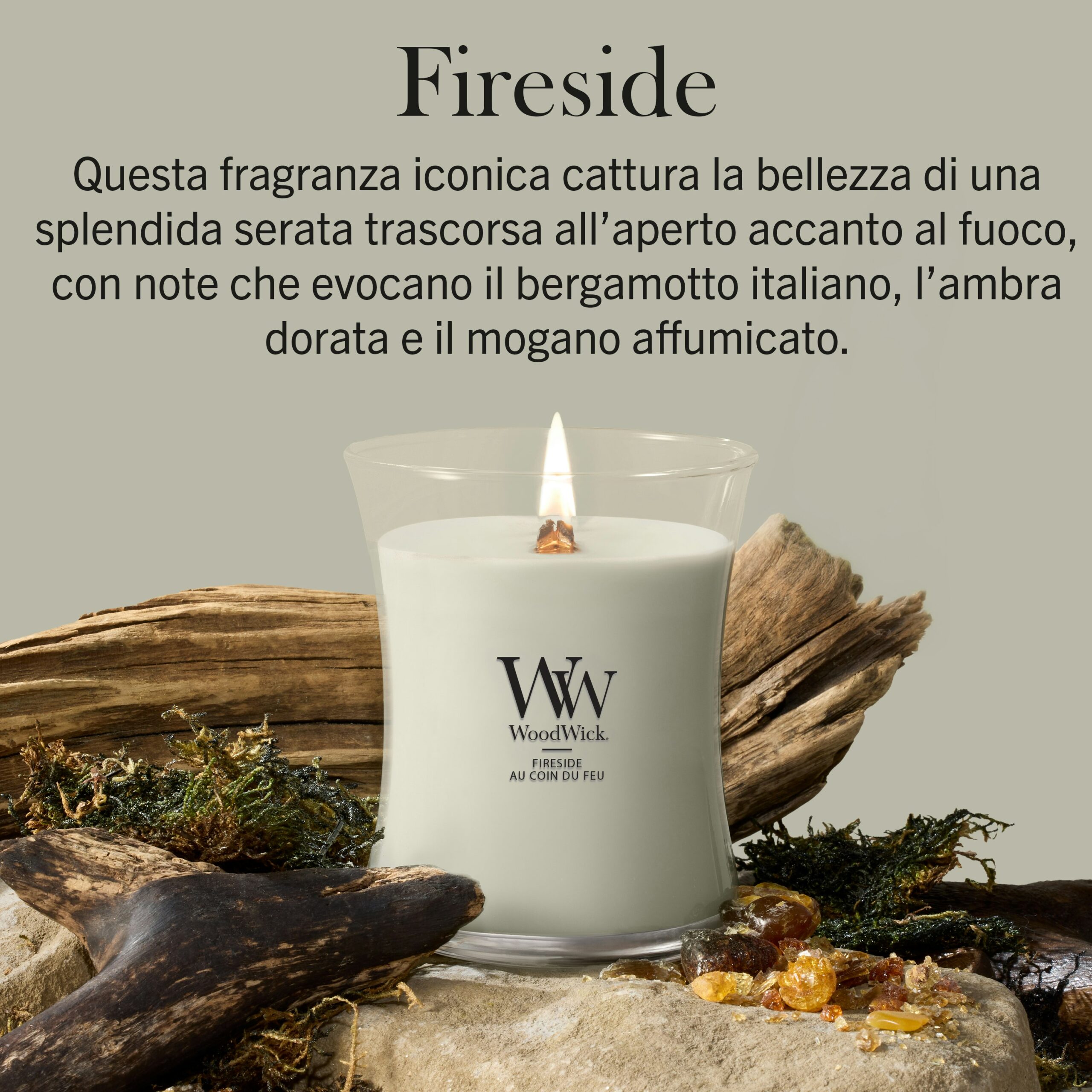 Fireside – Candela Media Woodwick Giara media Una lampada da caminetto - Candela Media Woodwick, di colore bianco, con una fiamma tremolante, è adagiata tra legni trasportati dal mare, pietre e muschio. Il testo in italiano sopra descrive le note olfattive: bergamotto italiano, ambra dorata e mogano affumicato.