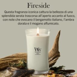 Un caminetto acceso: una candela “Candela Grande Woodwick” poggia su pezzi di legno e muschio. Il testo in italiano sopra descrive la fragranza, mettendo in risalto le note di bergamotto, ambra dorata e mogano affumicato.