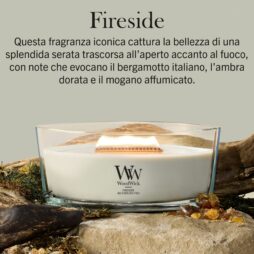 Una lampada da camino - Candela Ellipse, con stoppino in legno, arde su una superficie naturale, circondata da muschio, legno e pietre color ambra. Un testo in italiano descrive le note olfattive calde ed evocative della fragranza.