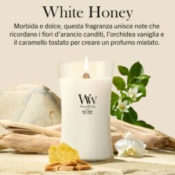 Una candela “White Honey Woodwick - Candela Grande” accesa, contenuta in un portacandela di vetro, poggia su una superficie beige, circondata da favi, mandorle, fiori bianchi e foglie verdi. Questa candela invitante riempie l’aria di note cremose di miele e delicate note floreali, mentre sopra di essa è riportata una descrizione della fragranza.