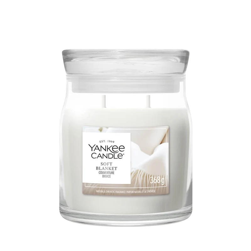 Soft Blanket – Giara Media – Yankee Candle 250 Punti Una candela in barattolo di vetro di medie dimensioni della Yankee Candle, denominata “Soft Blanket”, caratterizzata da un design accogliente con due stoppini e un’etichetta che raffigura una morbida coperta.