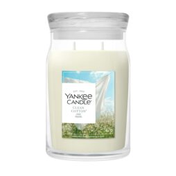 La candela Clean Cotton - Giara Grande di Yankee Candle è caratterizzata da una cera bianca e da un'etichetta con lenzuola bianche che si asciugano sotto un cielo azzurro, evocando il profumo di biancheria fresca e pulita.