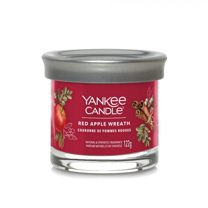 Red Apple Wreath – Tumbler Piccolo – Yankee Candle 100 Punti Una Yankee Candle nella fragranza "Red Apple Wreath", chiamata "Tumbler Piccolo", è racchiusa in un barattolo di vetro trasparente con un coperchio grigio. L'etichetta mostra immagini di mele rosse e bastoncini di cannella, con un peso dichiarato di 122 g.