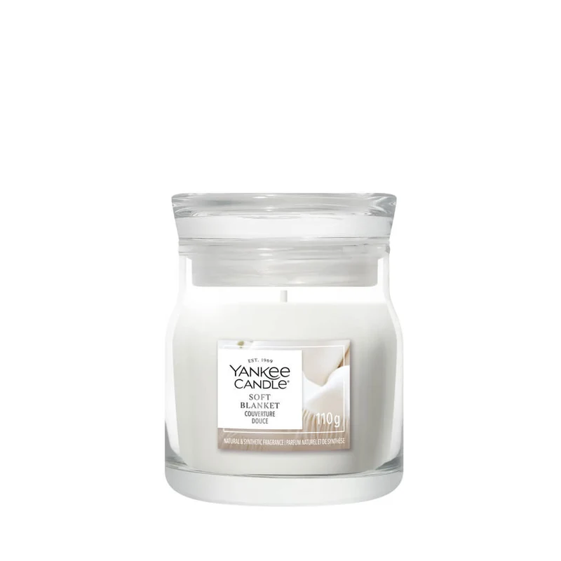 Soft Blanket – Candela Piccola – Yankee Candle 100 Punti Una piccola candela in bicchiere con l'etichetta “Soft Blanket - Tumbler Piccolo - Yankee Candle” e cera bianca. L'etichetta presenta un motivo dai toni tenui del beige e del bianco, e la candela spenta è raffigurata su uno sfondo bianco.