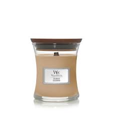 Una candela profumata WoodWick "Cashmere - Candela Piccola" beige in un barattolo di vetro trasparente con coperchio in legno marrone, caratterizzata dalla calda fragranza di Cashmere: perfetta per qualsiasi ambiente.