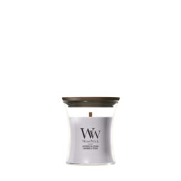 Una candela "Lavender and Cedar" - Candela Piccola - Woodwick, dai toni lavandati, contenuta in un barattolo di vetro ricurvo con coperchio in legno, sprigiona la fragranza rilassante di lavanda e cedro; sull'etichetta frontale è riportata la scritta "WoodWick Lavender & Cedar".