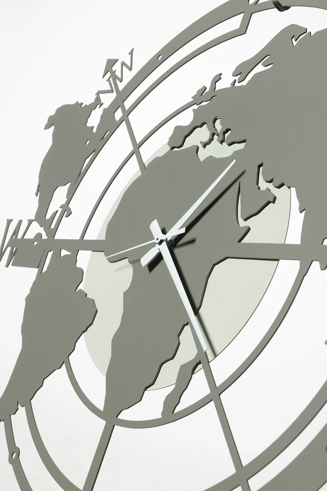 Orologio di design da parete Planisfero piccolo-Arti & Mestieri Complementi arredo saldi 2 Primo piano dell'Orologio di design da parete Planisfero piccolo-Arti & Mestieri, caratterizzato da un mappamondo in metallo grigio ritagliato con lancette bianche, su sfondo chiaro.