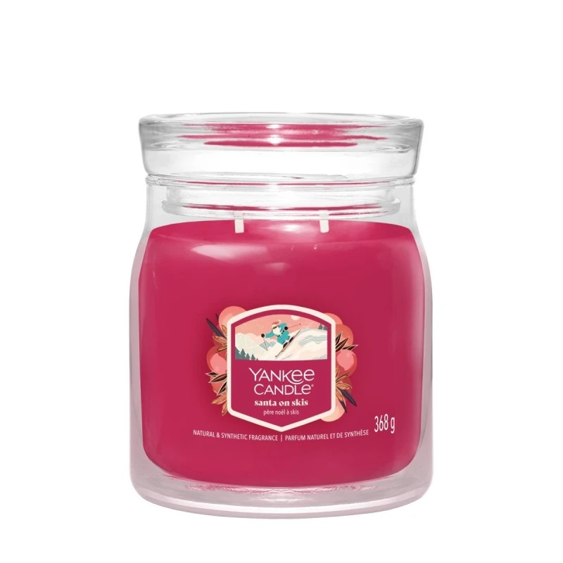 Santa On Skis – Giara Media – Yankee Candle 250 Punti Candela Giara Media Yankee Candle rosa "Santa On Skis" in barattolo di vetro trasparente con coperchio, con etichetta "Yankee Candle" e "Santa On Skis"; la candela a due stoppini pesa 368 g.