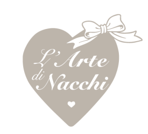 Un cuore color tortora con un fiocco bianco in cima riporta il testo "L'Arte di Nacchi" in caratteri corsivi, con un piccolo cuore bianco in basso.