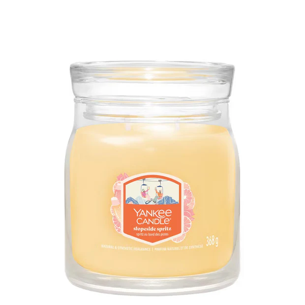 Slopeside Spritz – Candela Media – Yankee Candle 250 Punti Candela in barattolo di vetro di grandi dimensioni con cera di colore giallo chiaro. L'etichetta recita "Yankee Candle Slopeside Spritz" e raffigura una vivace scena sulle piste da sci. Questa media di 368 grammi di candela aggiunge un'atmosfera fresca ed esaltante a qualsiasi ambiente con la sua esclusiva fragranza Yankee Candle.