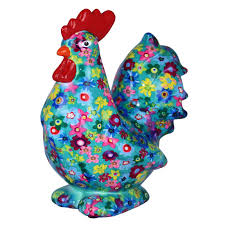 Il Gallo Maurice con frutti tropicali di Pomme Pidou è una statuina di gallo in ceramica con un vivace motivo di frutti tropicali su sfondo turchese, con pettine e becco rosso vivo e un aspetto espressivo e stravagante.