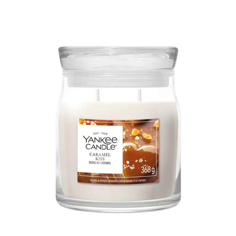 Caramel Kiss – Candela Media – Yankee Candle 250 Punti La candela in barattolo Caramel Kiss di Yankee Candle, presentata da Candela Media, ha cera bianca, due stoppini, un'immagine di un pezzo di caramello sull'etichetta e un peso netto di 368 g, perfetto per i momenti di intimità.