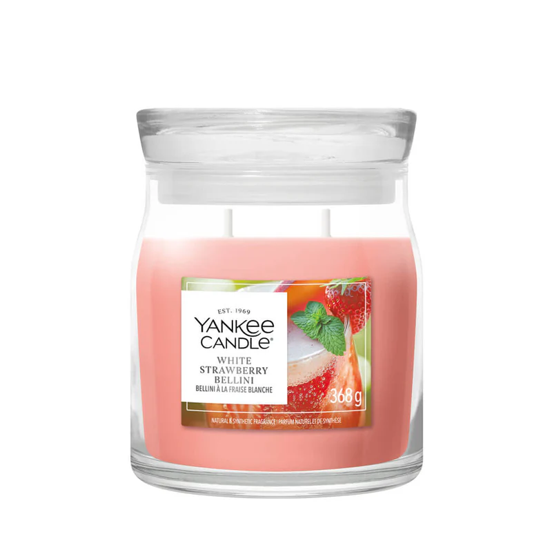 White Strawberry Bellini – Candela Media – Yankee Candle 250 Punti La candela "White Strawberry Bellini" - Candela Media - Yankee Candle presenta una cera rosa contenuta in un barattolo di vetro, chiuso da un coperchio rotondo trasparente e decorato con l'immagine di una bevanda alla fragola. Questa esclusiva candela a due stoppini diffonde una dolce fragranza in qualsiasi ambiente.