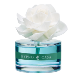 Una bottiglia di vetro trasparente con l'etichetta "Diffusore con rosa - Neroli - Hypno Casa - 60 ml" contiene un liquido blu, è sormontata da una rosa artificiale bianca dall'aspetto realistico e presenta un tocco di neroli che le conferisce un tocco di eleganza.