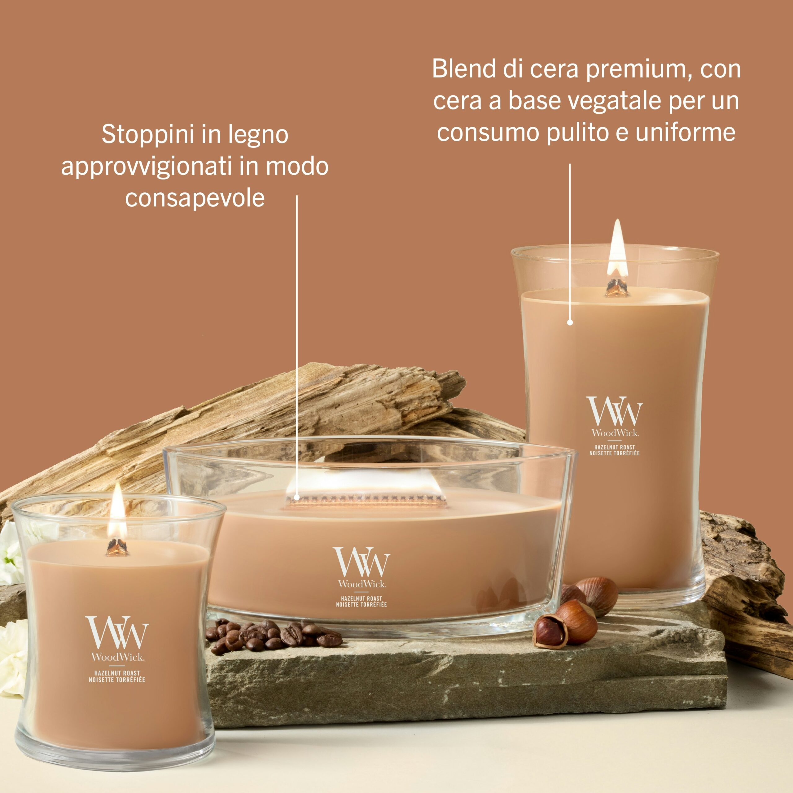 Hazelnut Roast – Candela Media – Wodwick Giara media 2 Three Hazelnut Roast - Candela Media - Le candele Wodwick in barattoli di vetro sono disposte ad arte con elementi decorativi in legno e chicchi di caffè, che ne esaltano l’aroma invitante. Il testo in italiano descrive caratteristiche quali gli stoppini in legno e una combustione pulita e uniforme grazie alla cera di soia di alta qualità: perfette per tutti gli appassionati di Candela Media che apprezzano sia l’eleganza che una fragranza avvolgente.