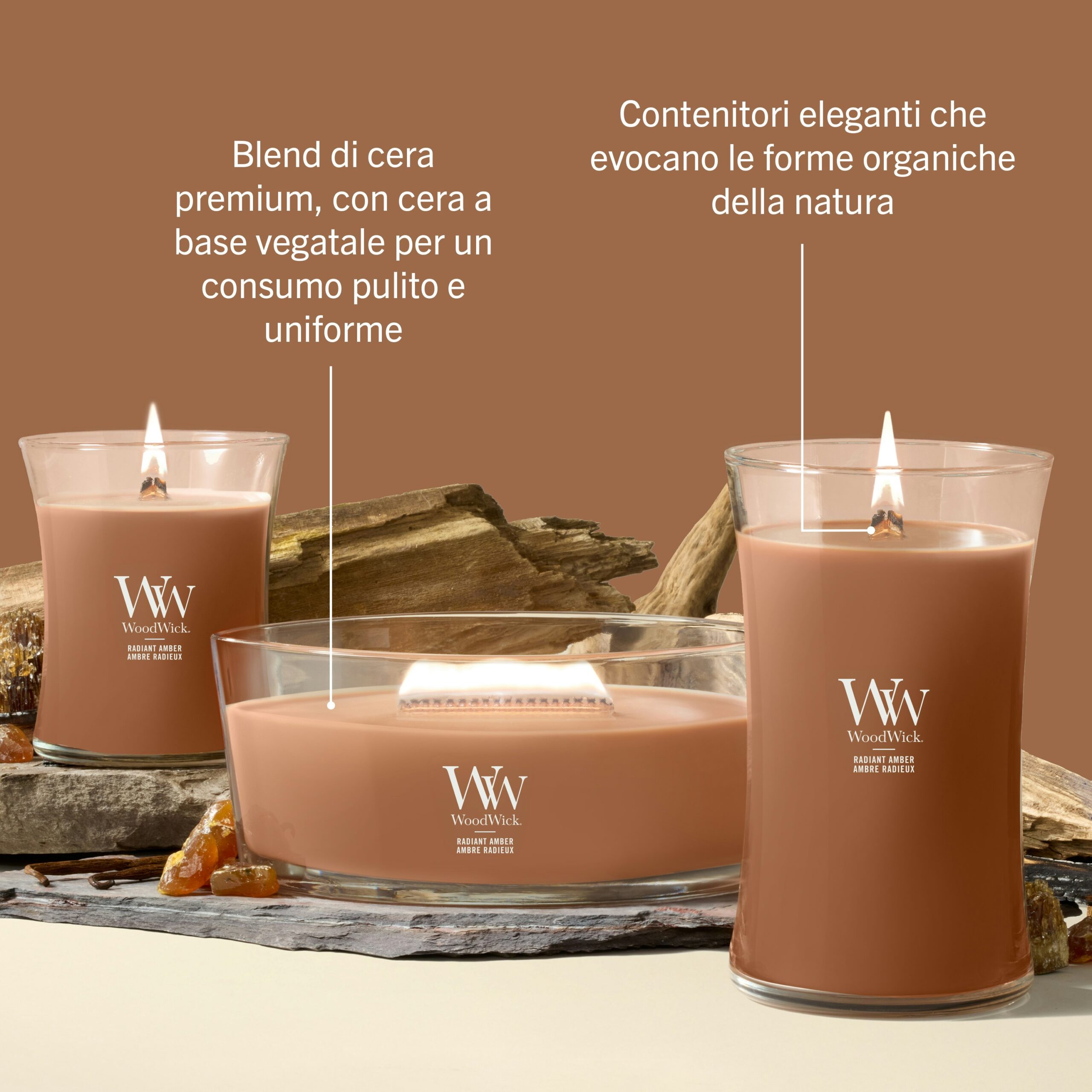 Radiant Amber – Candela Media – WoodWick Giara media 2 Tre candele Radiant Amber - Candela Media - WoodWick, ciascuna racchiusa in un contenitore di vetro trasparente dalla forma unica, poggiano su una superficie beige. Il testo in italiano sottolinea la qualità della loro cera vegetale di alta qualità e l’eleganza dei contenitori dalle forme organiche, mentre dettagli distintivi come il caratteristico design Candela Media e la delicata fragranza Radiant Amber contribuiscono alla loro raffinata sofisticatezza.