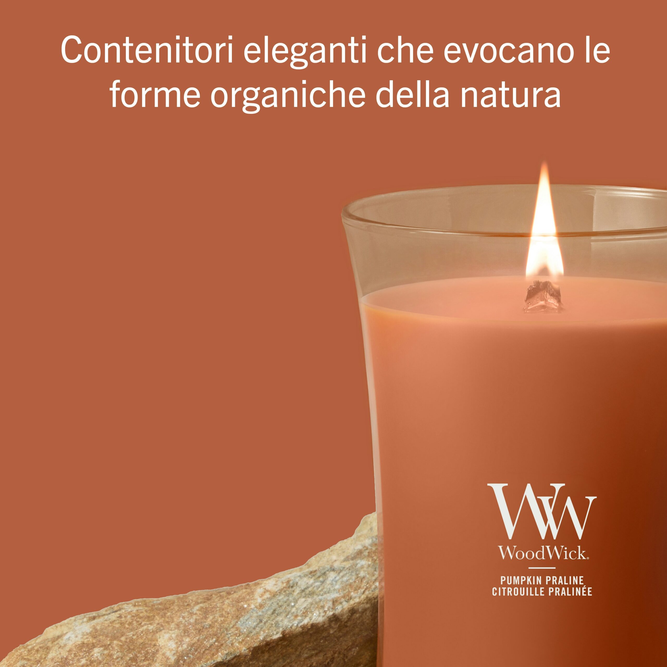 Pumpkin Praline – Candela Grande – Woodwick Giara Grande 2 Una candela Pumpkin Praline - Candela Grande - WoodWick risplende accanto a una pietra su uno sfondo arancione abbinato, accompagnata da un testo in italiano che mette in risalto gli eleganti contenitori ispirati alle forme organiche della natura. La fragranza calda e avvolgente Pumpkin Praline completa la scena.