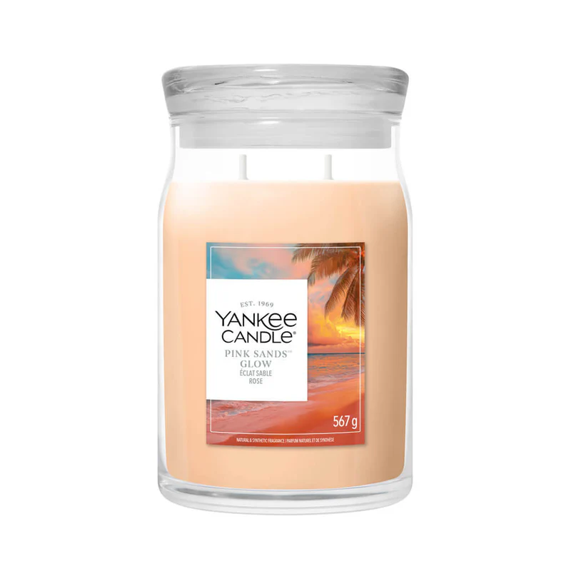 Pink Sands Glow – Candela Grande – Yankee Candle 350 Punti La candela "Pink Sands Glow - Candela Grande" di Yankee Candle è realizzata con cera color pesca chiaro e presenta un'immagine di un tramonto sulla spiaggia sul grande barattolo da 567 g, chiuso da un coperchio in vetro trasparente che crea un'atmosfera rilassante.