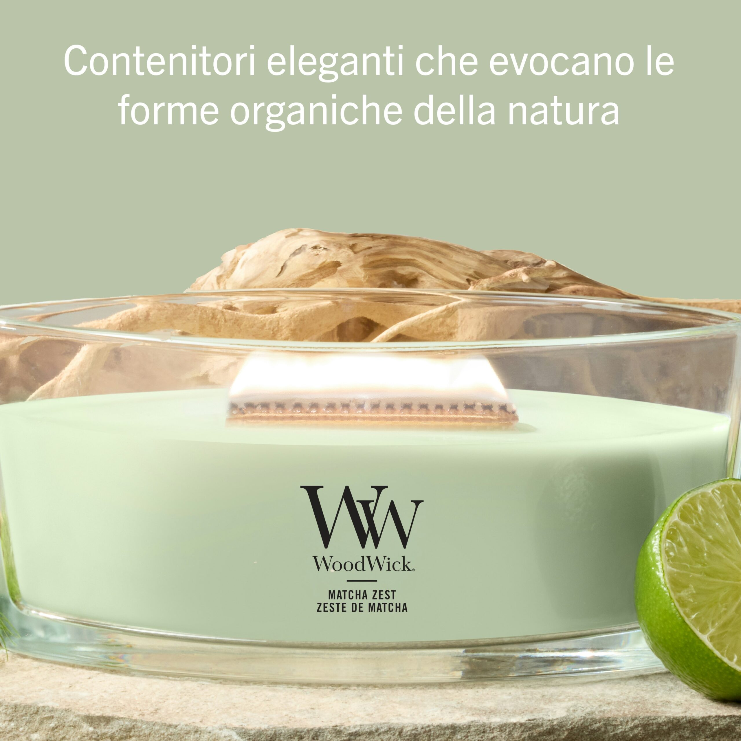 Matcha-Zest – Ellipse – Woodwick Ellipse 3 Una candela Matcha-Zest - Ellipse - Woodwick, con cera verde pallido racchiusa in un elegante contenitore di vetro, è esposta accanto a una fetta di lime fresco e a un pezzo di legno galleggiante. Il testo in italiano sopra sottolinea il design raffinato e ispirato alla natura del contenitore di forma ellittica, perfetto per aggiungere un tocco sofisticato a qualsiasi ambiente.