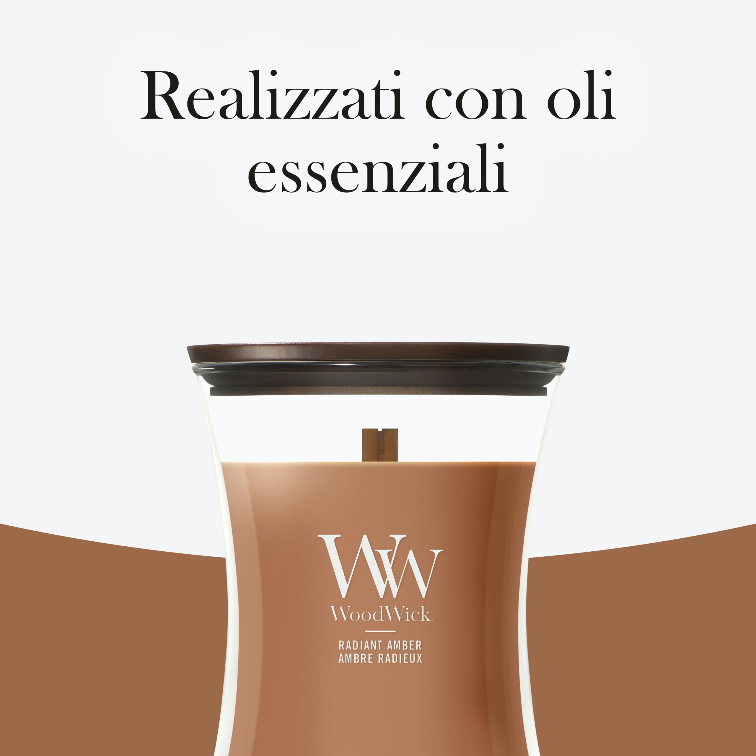 Radiant Amber – Candela Media – WoodWick Giara media 4 Una candela WoodWick Radiant Amber Candela Media di colore marrone, con l'etichetta "Radiant Amber" e la frase "Realizzati con oli essenziali" elegantemente riportata in alto in italiano.