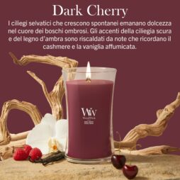 Una Candela Grande “Woodwick Dark Cherry” poggia su una superficie decorata con orchidee bianche, baccelli di vaniglia e ciliegie, il tutto su uno sfondo bordeaux intenso con una scritta in italiano in alto.