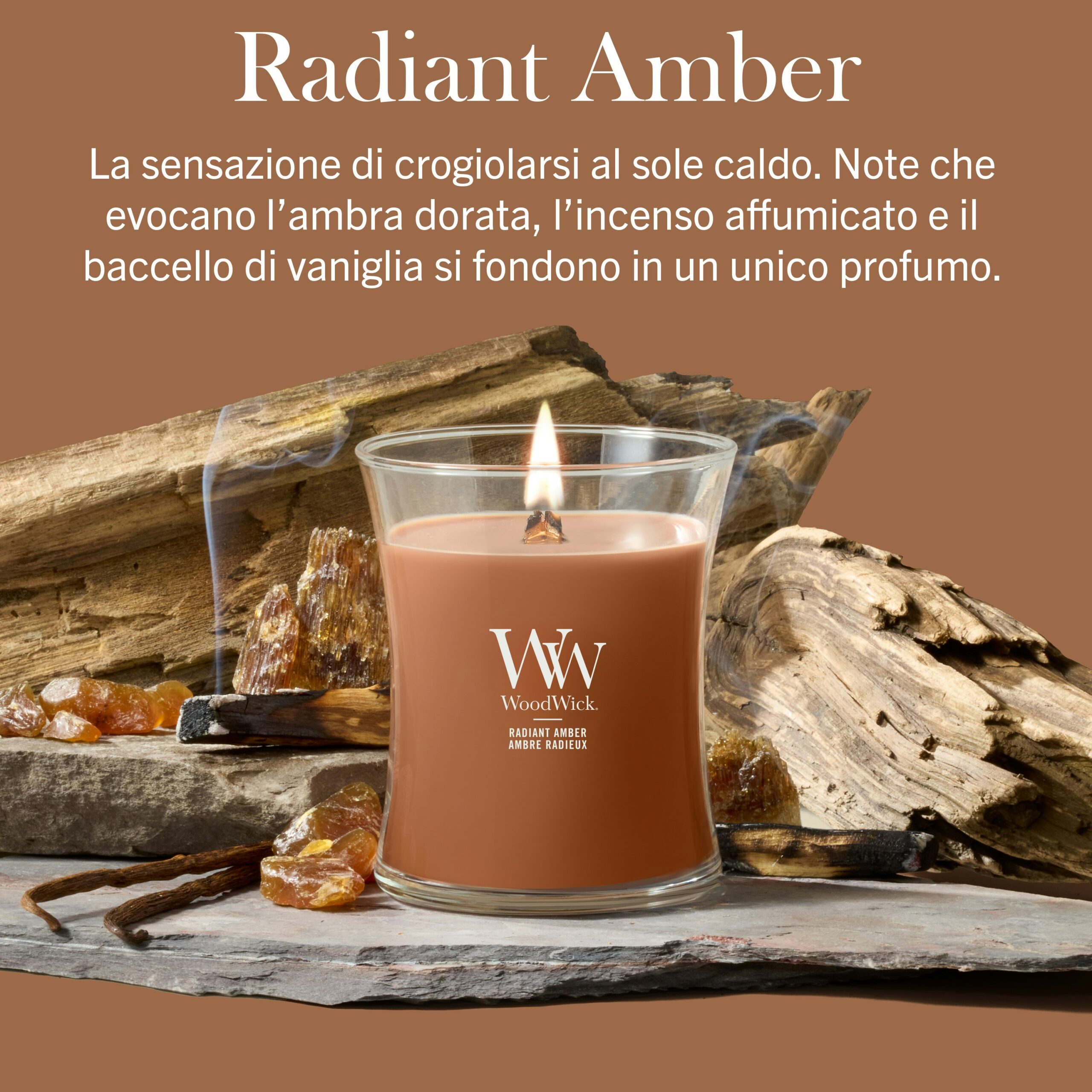 Radiant Amber – Candela Media – WoodWick Giara media Radiant Amber - Candela Media - WoodWick arde su una base di legno, circondata da pietre d’ambra, baccelli di vaniglia e fumo aromatico. Il testo in italiano mette in risalto le note calde, dorate, affumicate e vanigliate della fragranza Radiant Amber.