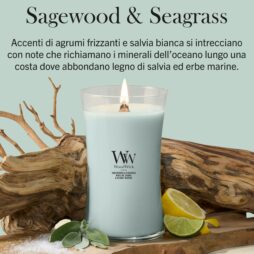 Sagewood and Seagrass – Candela Grande – Woodwick Giara Grande 2 Una grande candela Woodwick alla “salvia e alghe marine” in un contenitore di vetro azzurro è esposta accanto a fette di limone, sale marino, foglie di salvia e pezzi di legno galleggiante. Sull’etichetta si legge “WoodWick sagewood & seagrass”. Un testo in italiano descrive la fragranza della candela come una miscela di agrumi, legno di salvia e fresche note marine.