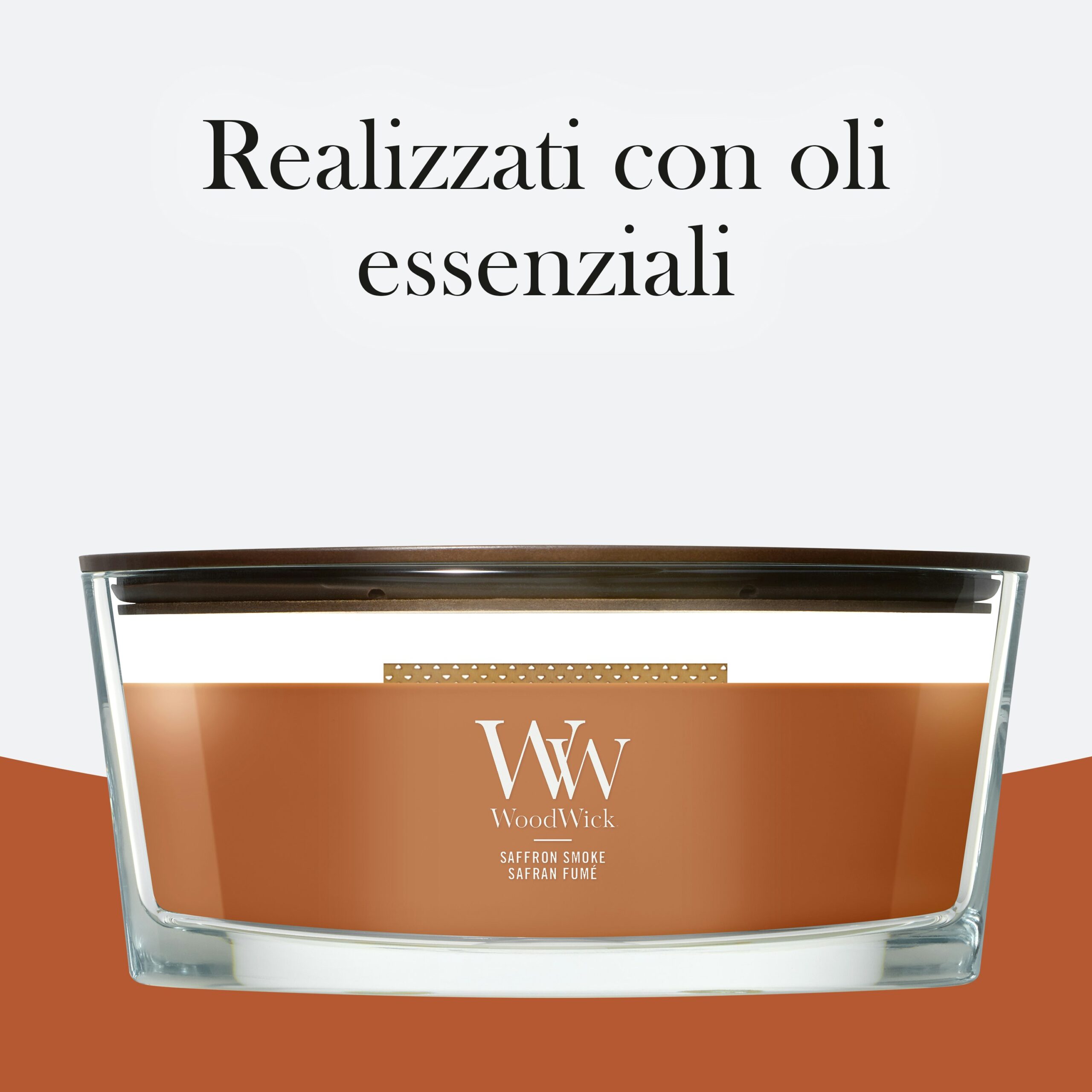 Saffron Smoke – Ellipse – WoodWick Ellipse 3 Una candela Saffron Smoke - Ellipse - WoodWick, con cera marrone, coperchio in legno ed etichetta, è esposta sotto una scritta in italiano che recita “Realizzati con oli essenziali”.