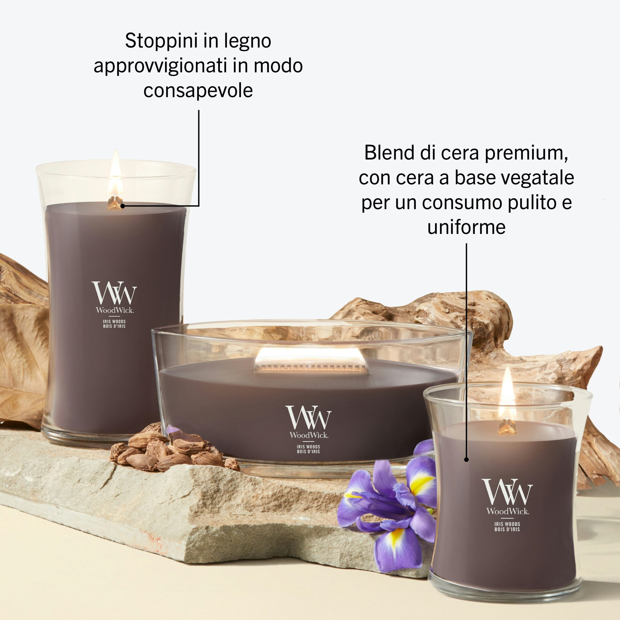 Iris Woods – Ellipse – Woodwick Ellipse 4 Sono esposte tre candele Iris Woods - Ellipse - Woodwick in contenitori di vetro viola, ciascuna dotata di uno stoppino in legno proveniente da fonti responsabili. La composizione è completata da pietre marroni e da un fiore viola. Il testo in italiano sottolinea la miscela di cera Iris Woods di alta qualità, che garantisce una combustione pulita, e l’uso di stoppini in legno provenienti da fonti etiche.