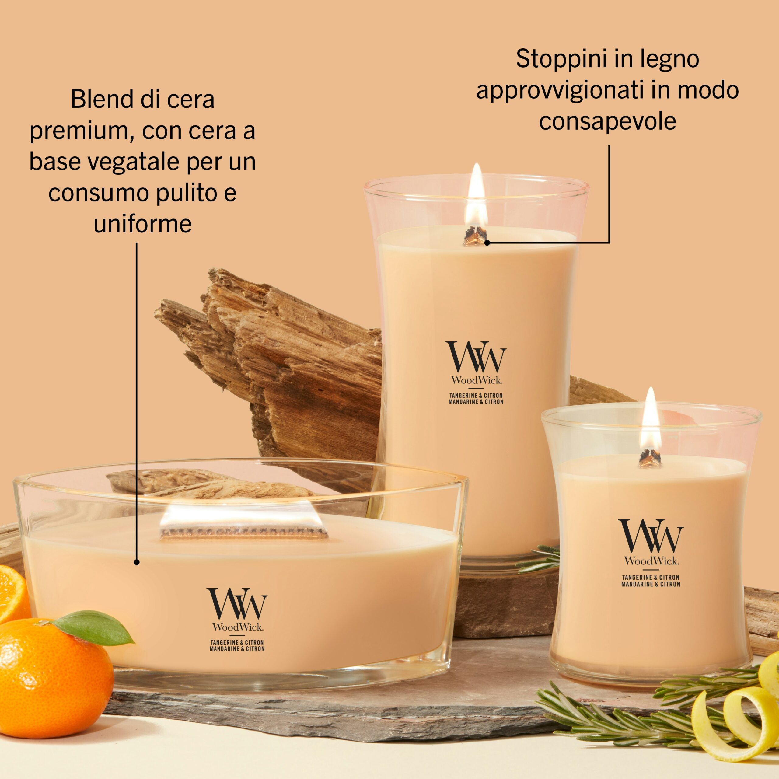 Tangerine & Citron – Candela Grande – WoodWick Giara Grande 4 Tre candele WoodWick della linea “Tangerine & Citrus - Candela Grande” poggiano su una superficie beige, circondate da pezzi di legno, un mandarino di colore arancione brillante e foglie verdi. Il testo in italiano ne descrive le caratteristiche — sottolineando la cera di origine vegetale e gli stoppini in legno brevettati — con note agrumate che creano un’atmosfera fresca e accogliente.